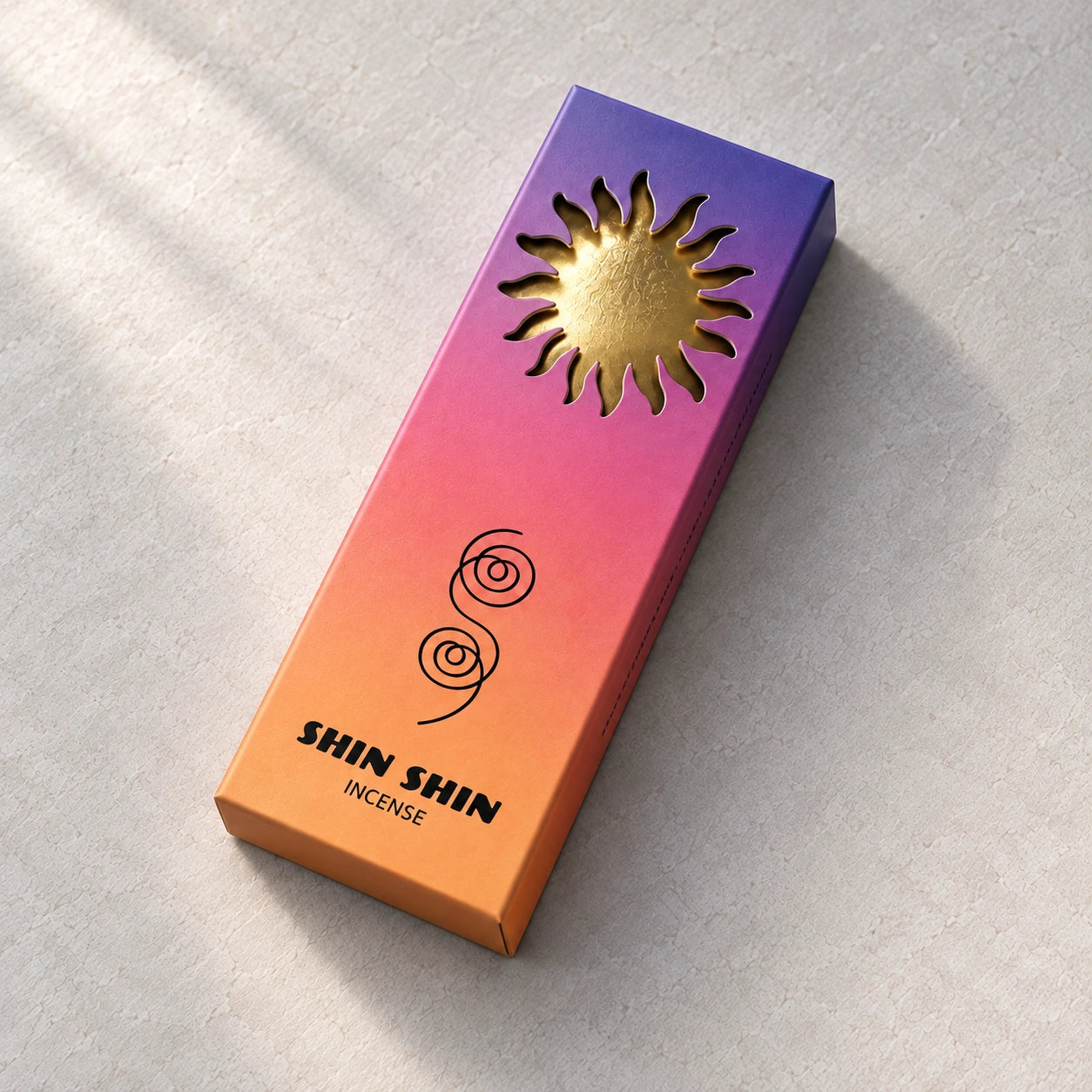 Closed Dawn incense box with a gold sun on a pale mineral background